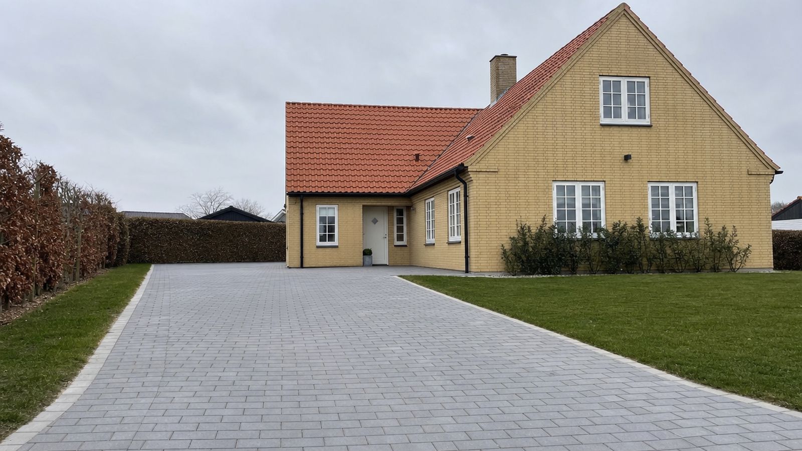 Dansk parcelhus med nyanlagt indkørsel i betonfliser og granitkant